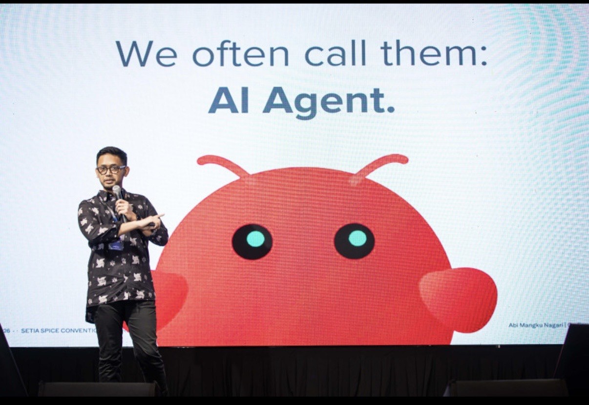 Abi Mangku on stage at PDX2026 in Penang, presenting AI agents in front of the talk's AI Agent slide